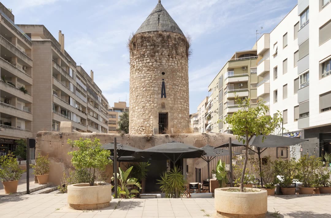 Plaza frente al molino con sombrillas — SĀNTAL Santa Catalina Palma