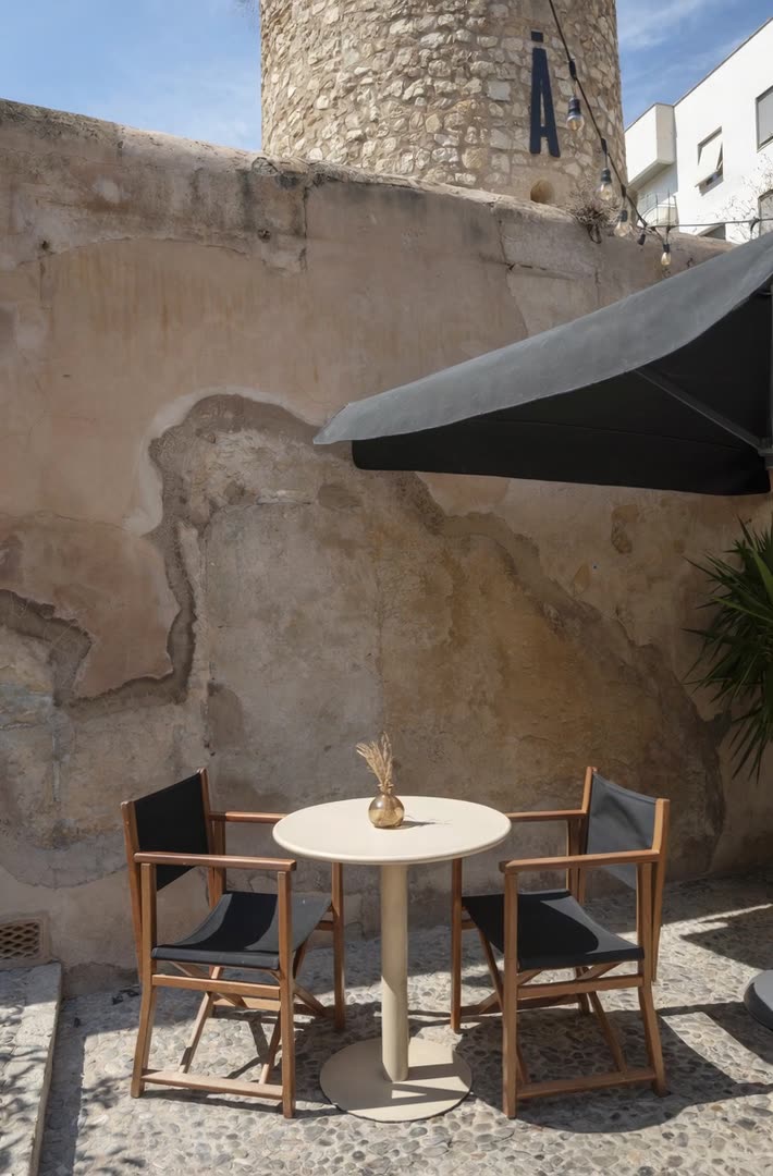 Mesa íntima en la terraza junto al muro histórico — SĀNTAL Palma