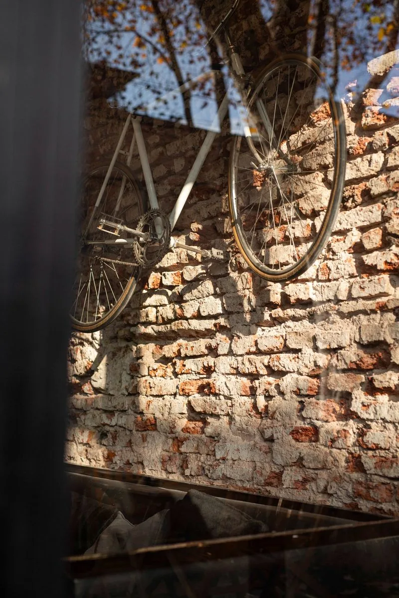 Bicicleta colgada en pared de ladrillo expuesto SĀNTAL Buenos Aires — detalle de interior con luz cálida