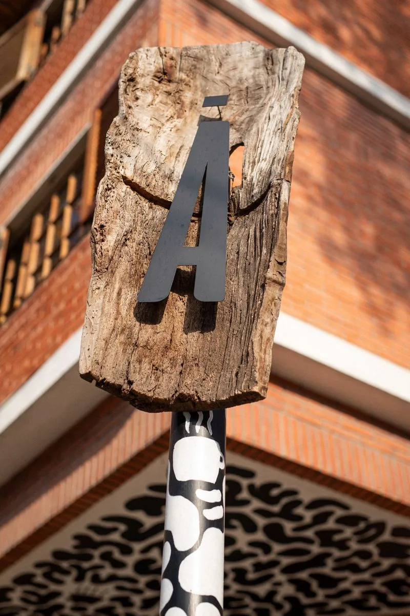 Letrero Ā SĀNTAL en madera rústica sobre poste — detalles de identidad de marca en la fachada de Colegiales