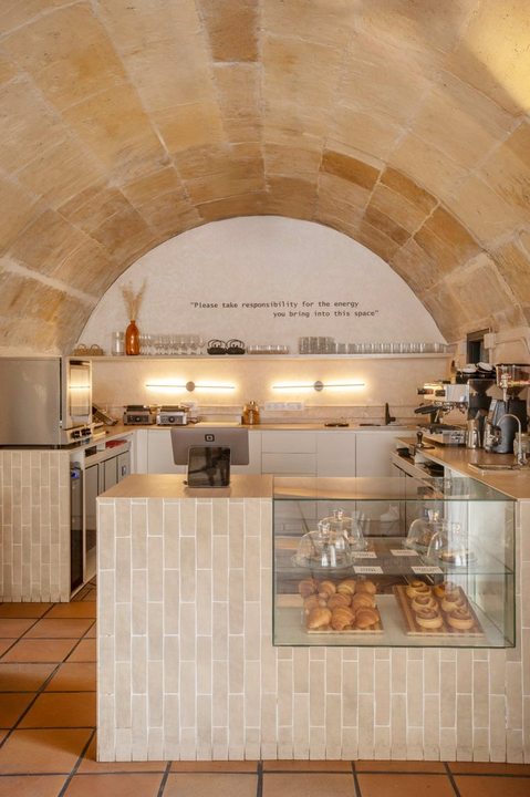 Barra artesanal SĀNTAL bajo bóveda de piedra histórica — bollería y espresso bar